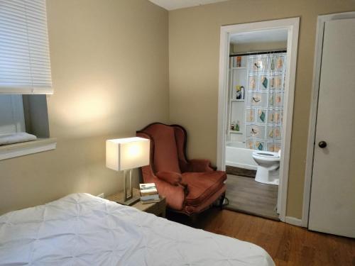 ein Schlafzimmer mit einem Bett, einem Stuhl und einer Lampe in der Unterkunft Stylish and Beautiful Condo in Frederick