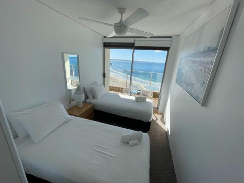 Dos camas en una habitación con vista al mar. en Oceanic 28 On The Beach, en Forster
