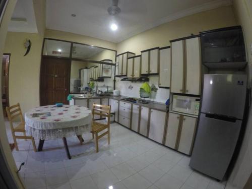 a kitchen with a table and a refrigerator at Pan Sutera Homestay Comfortable Bali Experience in Alor Setar
