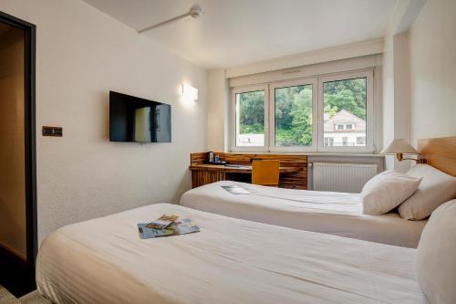 a hotel room with two beds and a television at Kyriad Montbeliard Sochaux in Montbéliard