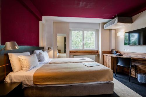 a hotel room with a large bed and a desk at Kyriad Montbeliard Sochaux in Montb&eacute;liard