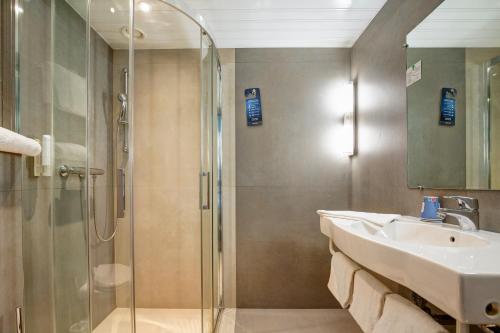 a bathroom with a sink and a shower at Kyriad Montbeliard Sochaux in Montb&eacute;liard