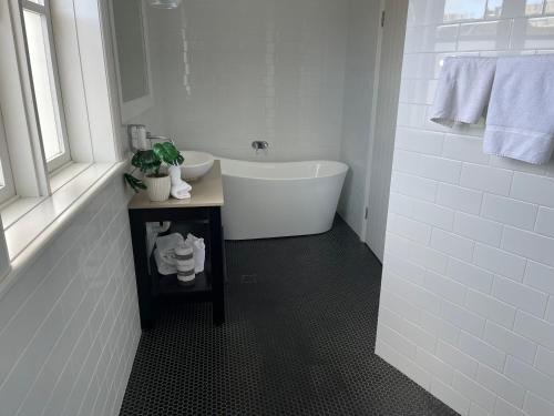 a white bathroom with a tub and a sink at Seabreeze Hotel in Nelson Bay