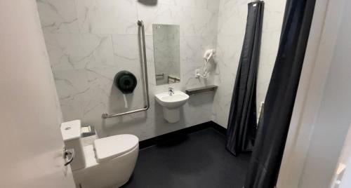 a white bathroom with a toilet and a sink at Tuatara Lodge in Invercargill
