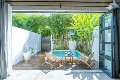 Un patio con sillas y una piscina. en Urban Oasis Loft by GORO, en Canggu