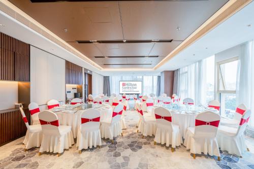 a conference room with white tables and red and white chairs at Hilton Garden Inn Hangzhou Xixi Zijingang in Hangzhou