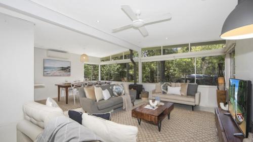 a living room with a couch and a table at Casa Bianca - Pearl Beach in Pearl Beach