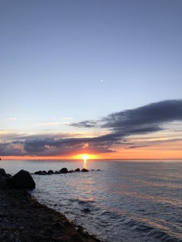 a sunset over the ocean with rocks in the water at MP 8 Steuerbord in Steinbeck
