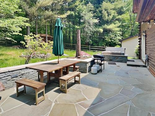 a patio with an umbrella and a table and benches at Wander Through the Woods in McHenry
