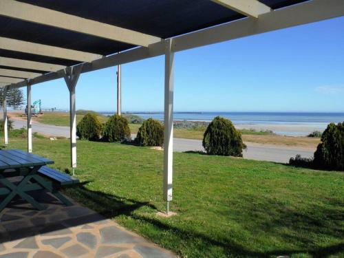 a picnic table under a pavilion with a view of the beach at Aquamarine in Port Moonta