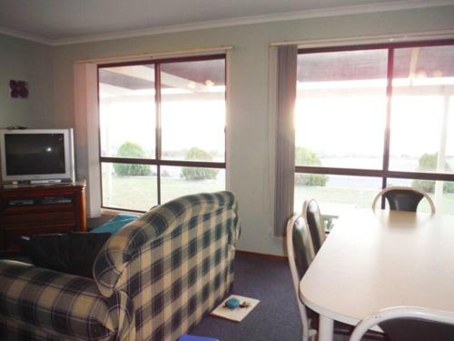 a living room with a couch and a table and windows at Aquamarine in Port Moonta