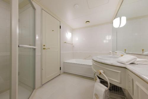 a white bathroom with a tub and a sink at Dai-ichi Hotel Tokyo in Tokyo