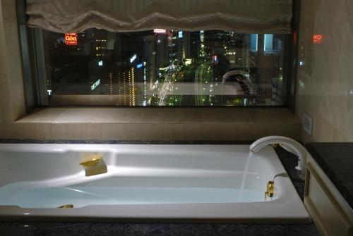 a bath tub in a bathroom with a window at Dai-ichi Hotel Tokyo in Tokyo