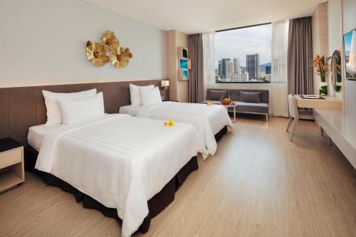 a hotel room with two beds and a desk at DQua Hotel in Nha Trang
