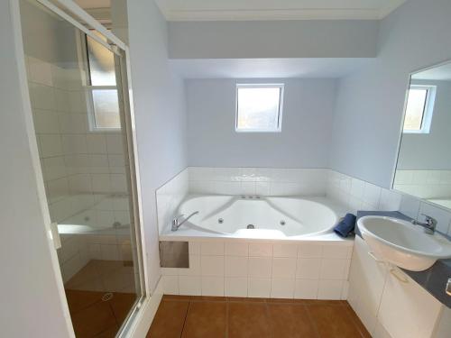 ein weißes Badezimmer mit Badewanne und Waschbecken in der Unterkunft Osprey Holiday Village Unit 118 in Exmouth