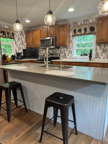 a kitchen with a sink and a counter with two stools at Mossy Bear Retreat in Chestertown