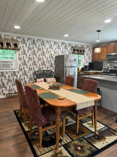 a kitchen with a wooden table with chairs and a refrigerator at Mossy Bear Retreat in Chestertown