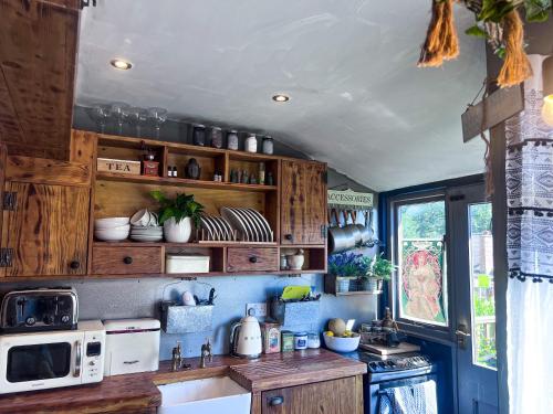 a kitchen with wooden cabinets and a white microwave at Travel Back in Time Fairy Cottage on the Cobbles an Experience Property in Haworth
