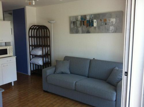 a living room with a blue couch and a kitchen at Appartement Cap D'Agde in Cap d'Agde
