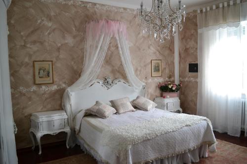 a bedroom with a white bed and a chandelier at Le Bouganville Apartment in Desenzano del Garda