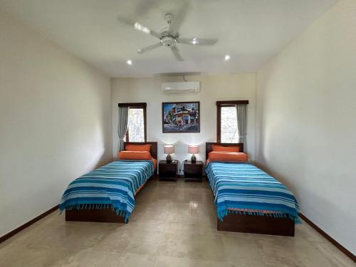 a bedroom with two beds and a ceiling fan at Villa Ponjok Batu Residence in Bukti