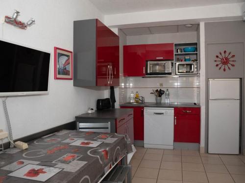 Elle comprend une petite cuisine avec des placards rouges et une télévision. dans l'établissement T2 Cabine 4 pers. avec balcon, clim, parking, à 10m de la plage du Lavandou - FR-1-803-66, au Lavandou