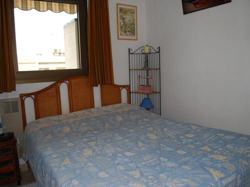 une chambre avec un lit avec une couette bleue et une fenêtre dans l'établissement 2 Pièces au Centre Ville, 4 Couchages, Proche Plage, Terrasse, Clim, Parking - FR-1-803-65, au Lavandou