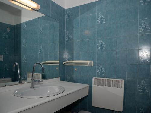 La salle de bains est pourvue de carrelage bleu, d'un lavabo et d'un miroir. dans l'établissement Studio face mer avec terrasse - 2 pers, parking, plage et centre ville à pied - FR-1-803-67, au Lavandou