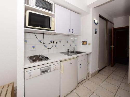 une cuisine avec des armoires blanches, un évier et un micro-ondes dans l'établissement Studio cabine 4 pers, bord de mer, clim, parking, WIFI - FR-1-803-60, au Lavandou