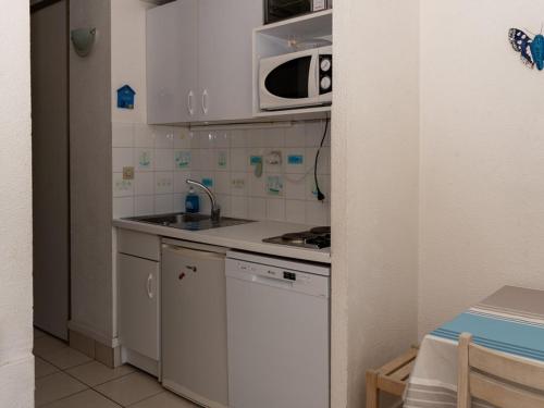une cuisine avec un évier et un micro-ondes dans l'établissement Studio cabine 4 pers, plage à 10m, parking, clim, WiFi, animaux acceptés - FR-1-803-63, au Lavandou