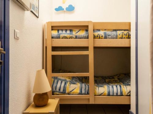 Ce lit se trouve dans un dortoir doté de 2 lits superposés et d'une lampe. dans l'établissement Le Lavandou, studio cabine - 4 pers, plage à 10m, clim, parking, tennis - FR-1-803-64, au Lavandou