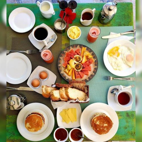 a table topped with plates of breakfast foods and coffee at La Diguoise in La Digue