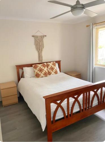 Un dormitorio con una cama grande con ventilador de techo. en Gwen, en Marcoola