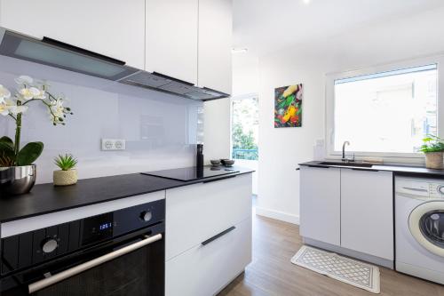 une cuisine avec des armoires blanches et une laveuse et une sécheuse dans l'établissement Superbe appartement et vue - 4 pers - Parking, à La Baule