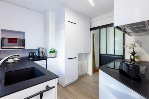 une cuisine avec des armoires blanches et un comptoir noir dans l'établissement Superbe appartement et vue - 4 pers - Parking, à La Baule