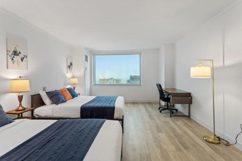 a hotel room with two beds and a desk and a window at Sleep 6 Stylish 1BR 2BA Beachfront by CozySuites in Atlantic City