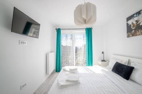 a white bedroom with a large bed with blue curtains at Modern Coresi Studio - Free Private Parking by MM Host in Braşov