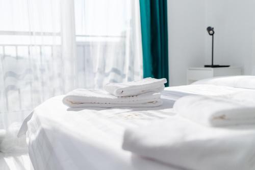 two white towels are stacked on a white bed at Modern Coresi Studio - Free Private Parking by MM Host in Braşov