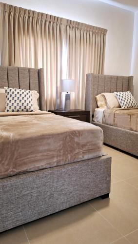 a bedroom with two beds and a window with curtains at Atlantic Paradise Cabrera in Arroyo Azul