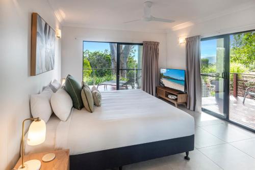 a bedroom with a large bed and a balcony at Compass Point on Hamilton Island by HIHA in Hamilton Island