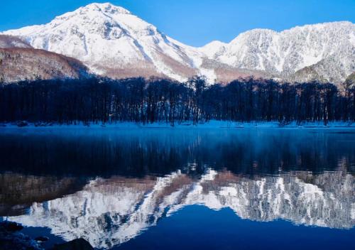 a mountain reflecting in a lake with snow covered at 筋肉と自然と遊ぶ宿 田島館 in Takayama