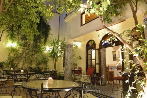 an outdoor patio with tables and chairs and trees at Riad Jardin Chrifa in Fès