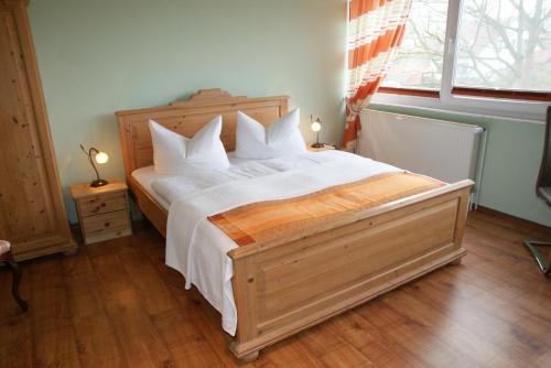 a bedroom with a large bed with white sheets and a window at Ferienwohnungen im Haus Bi Henny in Baabe