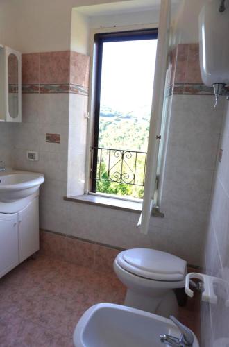 a bathroom with a toilet and a sink and a window at Eden - Nel Cuore Della Natura in Compignano