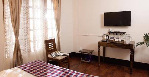 a bedroom with a bed and a desk with a television at April Springs Home Stay in Shillong