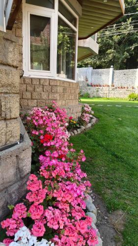 a bunch of pink flowers in front of a house at Sparsh Resort, A Boutique Stay - Just 2kms uphill from Mall Road, near Old Manali in Manāli