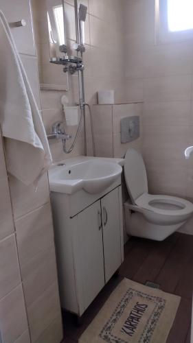 a white bathroom with a toilet and a sink at ЕкоПойнт in Chernomorets