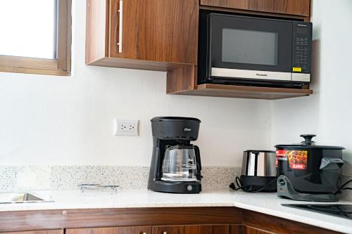 a kitchen counter with a coffee maker and a microwave at Villas y Casa Dìwö - Puerto Viejo in Hone Creek