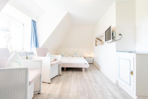 a white room with a bed and chairs at Haus Südkap in Hörnum