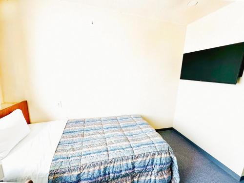 a bedroom with a bed in a room at Station Business Hotel Tenshukaku in Hitoyoshi